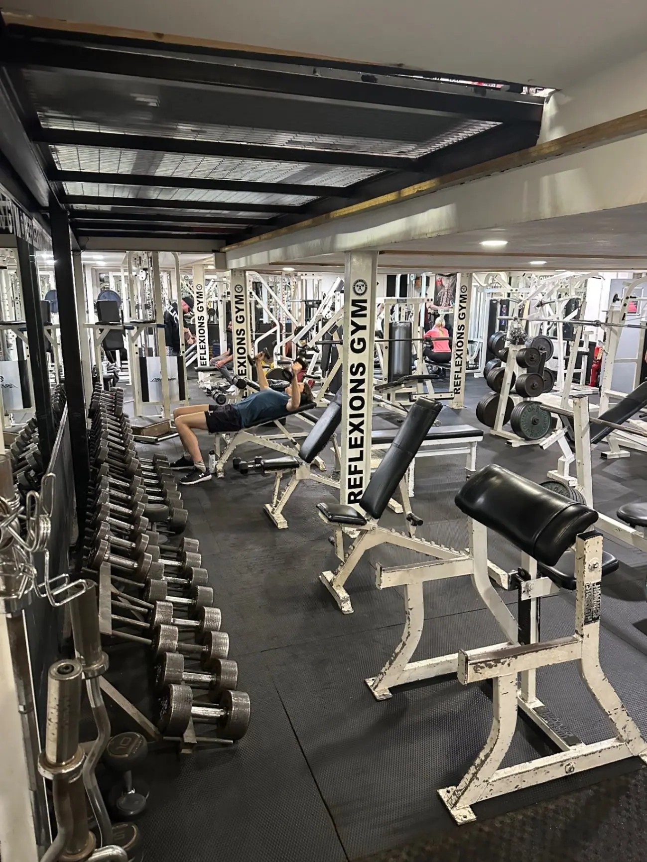 A member training on a bench among the weights at Reflexions Gym